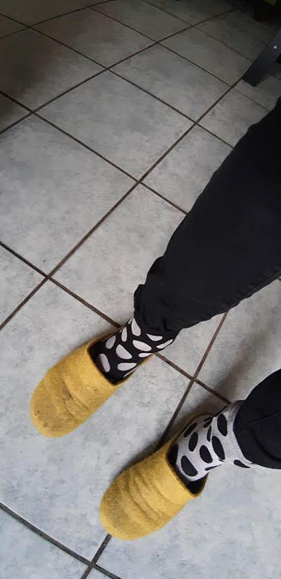 Beispiel-Foto Looking for Patterns. Das Handy-Foto zeigt einen Ausschnitt.Zwei Füße in gelben Pantoffeln  tragen einen weißen Socken mit schwarzen Punkten und eine schwarzen Socken mit weißen Punkten. Der Boden ist mit quadratischen hellen Kacheln gefliest.