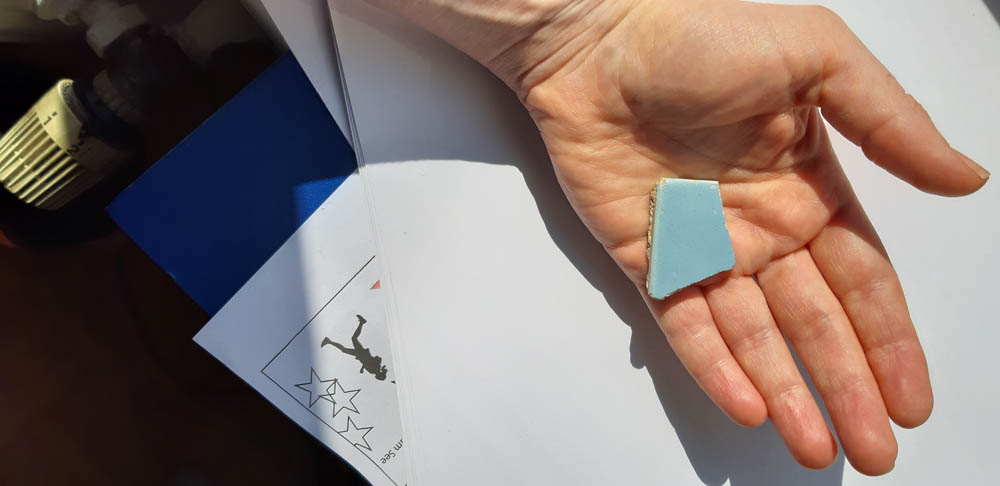 Foto-Beispiel zum Starterkit ein Stück Himmel. Das Foto ist aus der Vogelperspektive aufgenommen. Eine Hand hält ein kleines rautenförmiges Stück Himmel. Material ist nicht zu erkenne. Die Hand ist ausgestreckt.