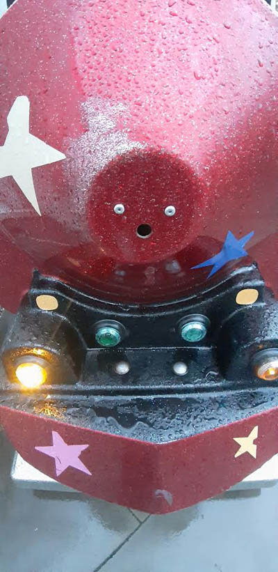 Beispiel-Foto zum Startkit #gesichtersindüberall  Zwei Schrauben und ein kleines Loch an der Vorderseite eines roten Spielgerätes sehen aus wie ein Gesicht. Eine Lampe leuchtet. Die Lampe gegenüber funktioniert nicht. Ein paar Sterne sitzen auf dem Rot.