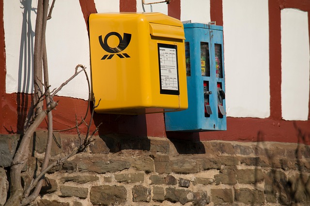 Beispiel-Foto. Briefkasten und  blauer Kaugummi-Automat an einer gestreiften Hauswand. 