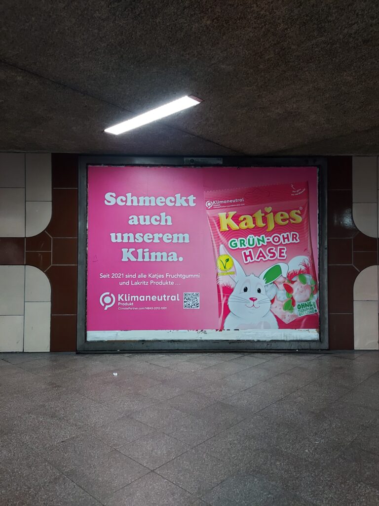 Foto-Beispiel zum Thema Osterhasen-Go! Werbeplakat in rosa für eine Süßigkeit in Hasenform in einer Unterführung. Die Wand ist verwackelt. Eine Neonröhre beleuchtet das Geschehen.