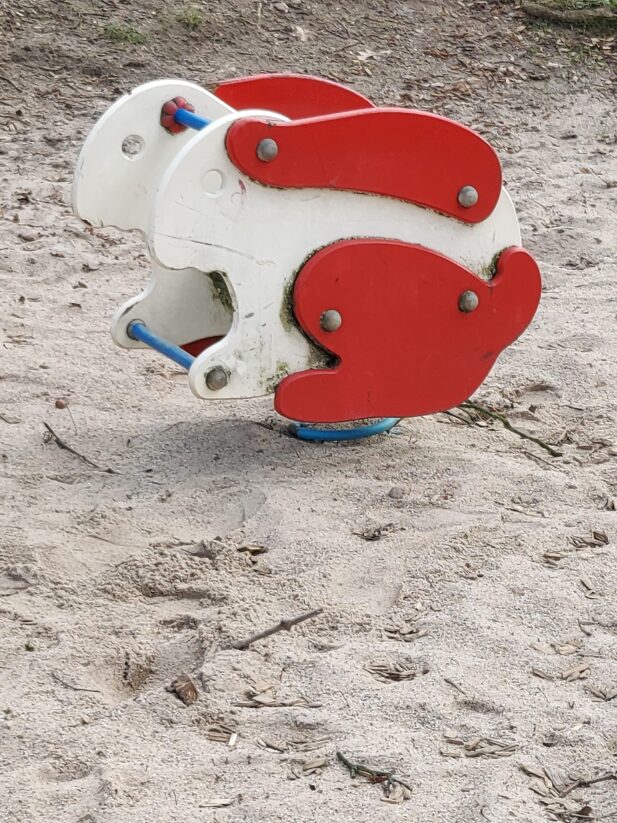 Beispiel-Foto zum Thema Osterhasen-GO in der Stadt. Spielgerät aus Holz in Hasenform, rote Ohren, weißer Körper, rote Beine, steht auf einer Sandfläche