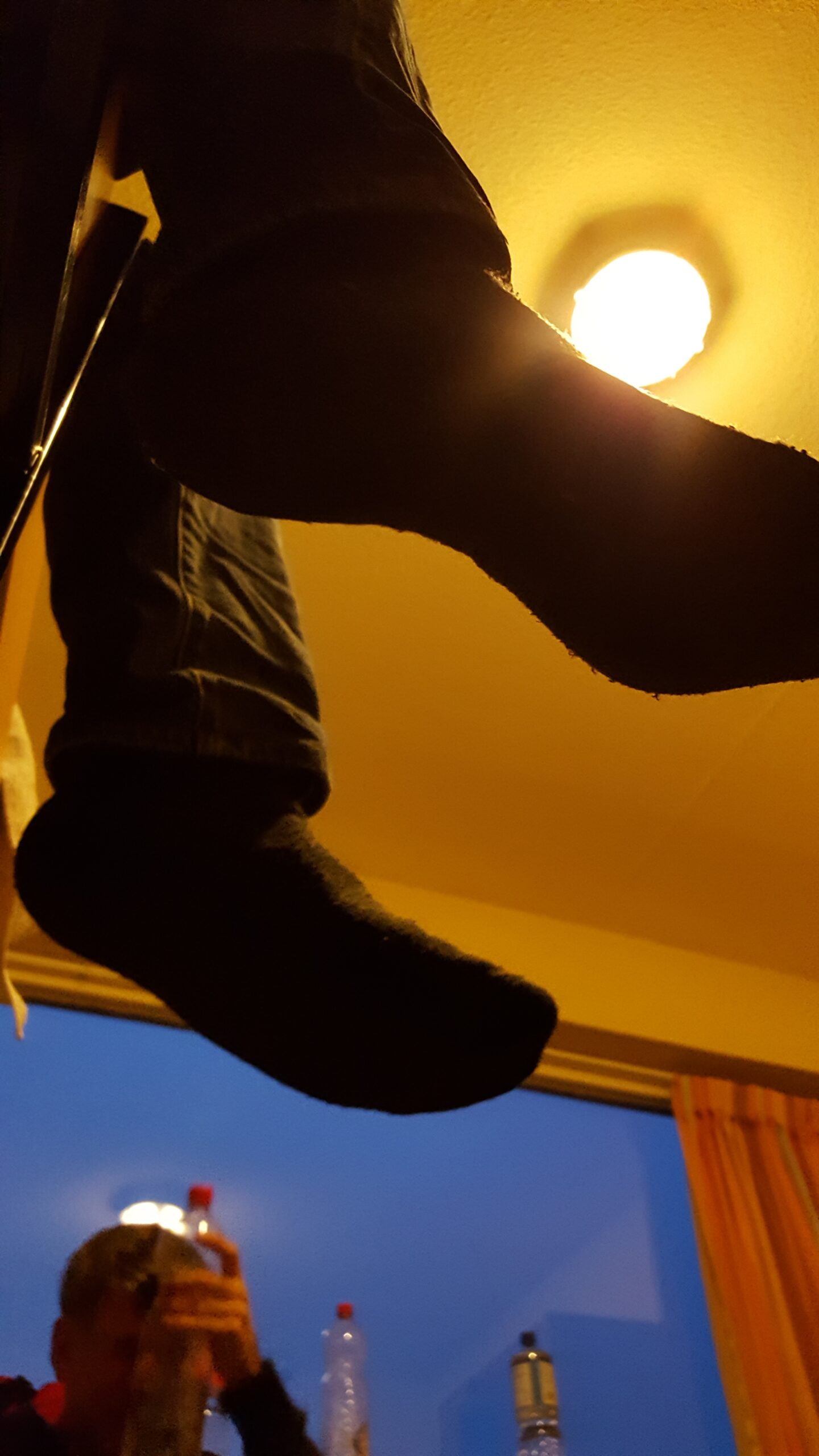 Beispiel-Foto zum Thema #Handy-Malerei. Reihe Primärfarben. Zu sehen ist der Blick auf zwei Beine und Füße ohne Schuhe im Gegenlicht. Die Decke sieht gelb aus. Zusammen mit einem rosafarbenen Vorhang und dem blauen Himmel entsteht der Eindruck eines Primär-Dreiklangs.
