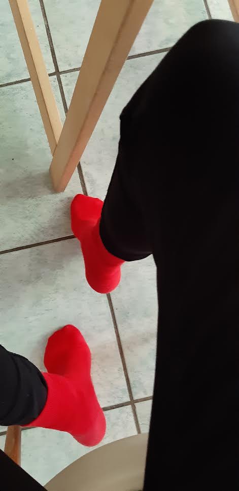 Beispiel-Foto zum Thema "Take 2" . Zwei Füße in roten Socken tanzen auf dem Küchenboden mit quadratischen Fliesen.