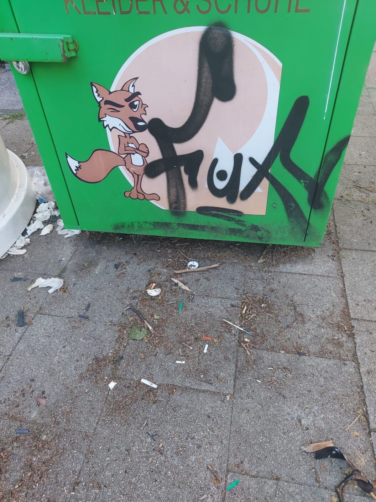 Beispiel-Foto zum Thema #cityzoo. Zu sehen ist ein grüner Kleider-Container, davor eine Comiczeichnung eines Fuchses, der zwinkert und beide Arme verschränkt hat, außerdem ein aufgesprühtes tag, es ist der Schriftzug Fuxy 