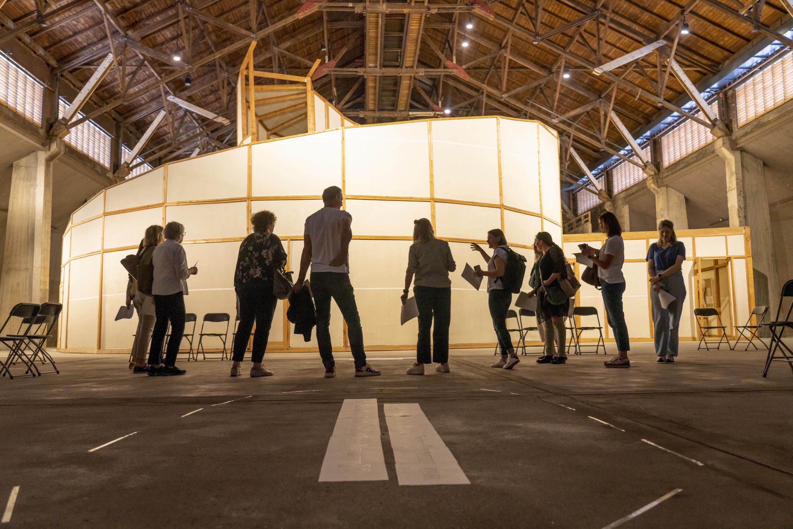 Durch Kunst ins Denken und Sprechen kommen, Workshop "Du und D-eine Gegenwart - Mach doch mal Ideen" , Maßkonzeption für die Stiftung Zollverein in Essen. Neun Personen stehen vor dem Kunstwerk "Palace of Projects" von Ilya und Emilia Kabakov. Die Personen halten Zettel mit den Proketiteln in den Händen.